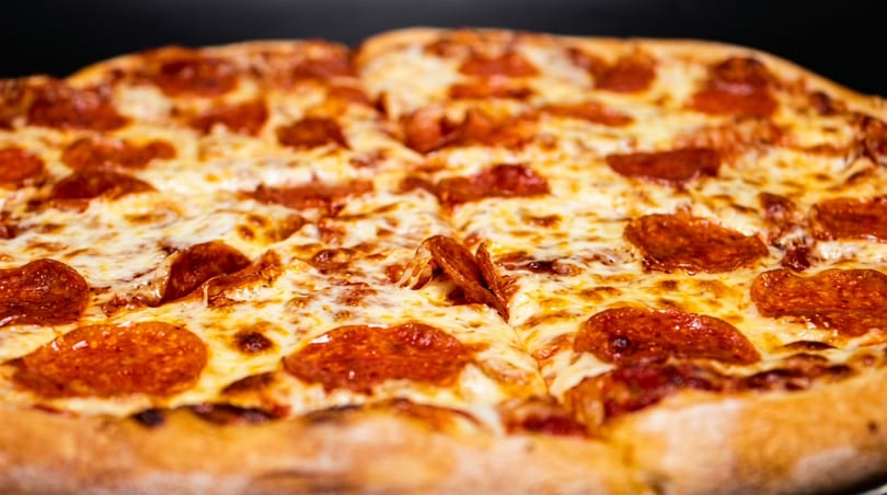 Close-up of a whole, sliced pepperoni pizza with melted cheese and crispy pepperoni.